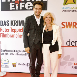 Oliver Mommsen und Sabine Postel vor der Sponsorenwand von Tatort Eifel